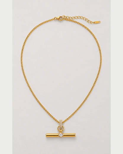 Delphine gold pavé toggle necklace on a pale dove-grey background