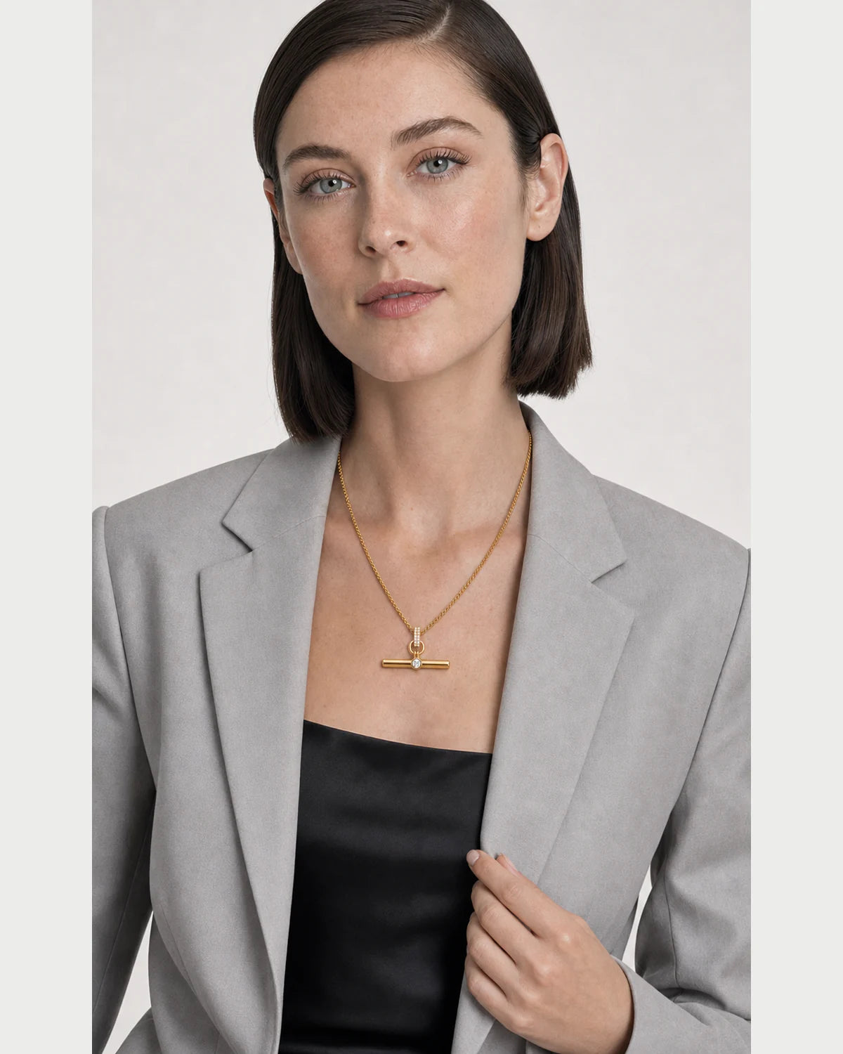 Model holding her blazer lapel while wearing the Delphine pavé toggle necklace