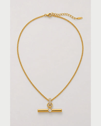 Delphine gold pavé toggle necklace on a seamless pale dove-grey background