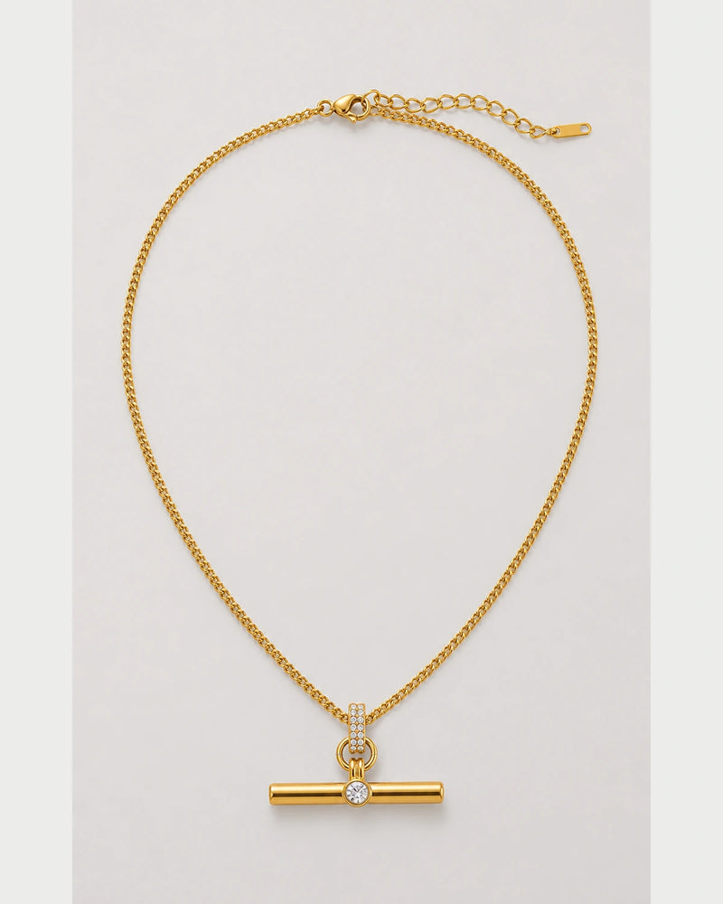 Delphine gold pavé toggle necklace on a seamless pale dove-grey background