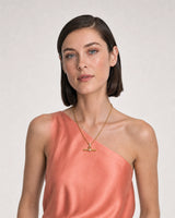 Model in coral silk and ivory summer linen wearing the Delphine pavé toggle necklace