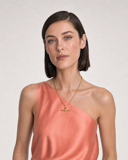 Model in coral silk and ivory summer linen wearing the Delphine pavé toggle necklace