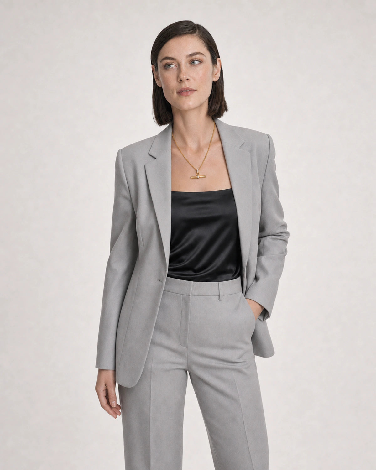 Wide grey-studio editorial portrait with the Delphine gold toggle necklace