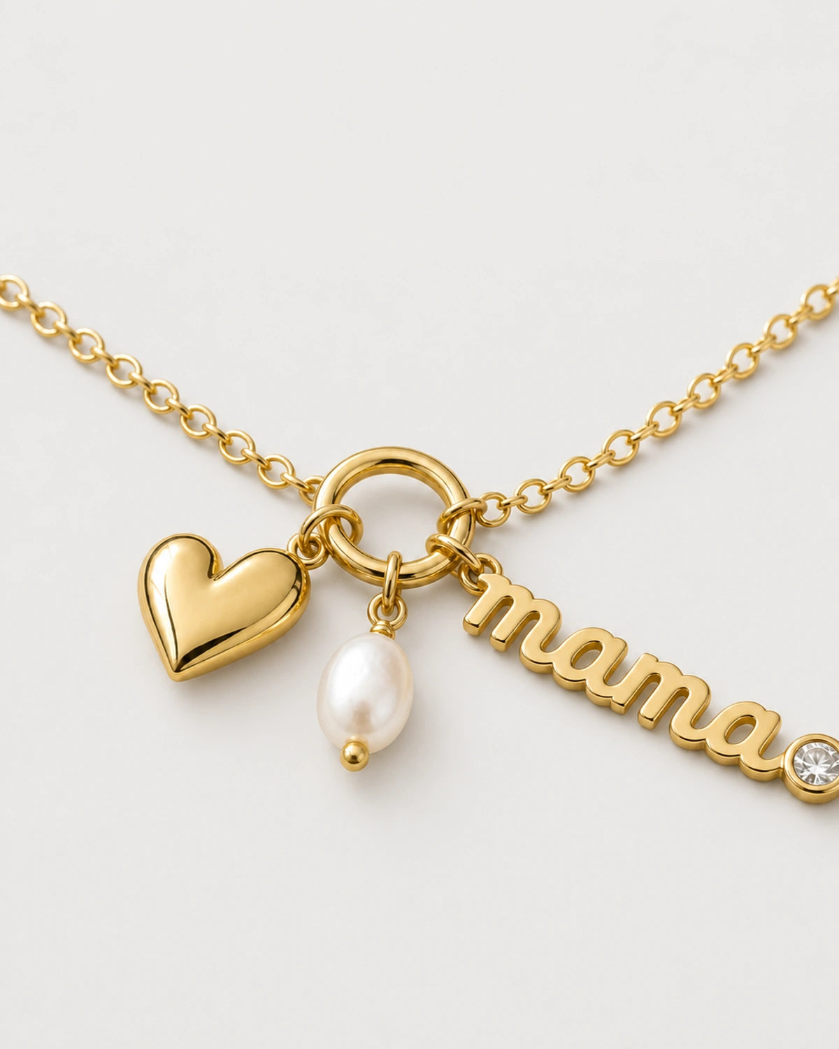 Macro of the Elara mama charm, puffed gold heart and oval white pearl