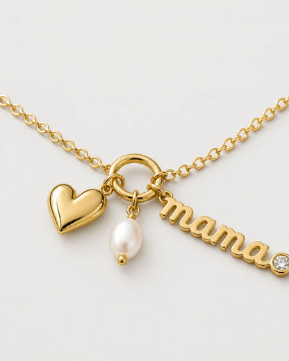 Macro of the Elara mama charm, puffed gold heart and oval white pearl