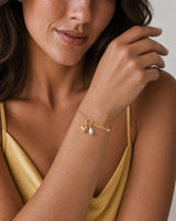 Close wrist view of the Elara mama, heart and pearl charms with butter-yellow silk