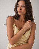 Human-scale summer portrait of the model wearing the Elara mama charm bracelet