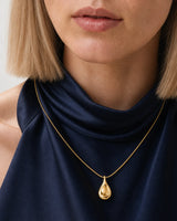 Complete worn macro of the Elara gold sculptural droplet necklace on Helena