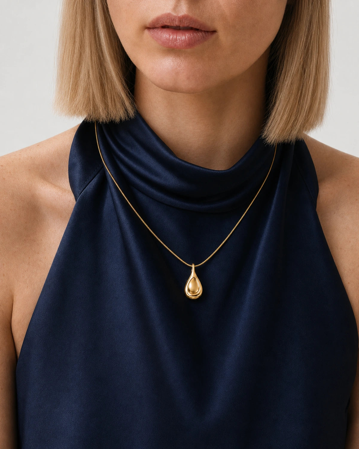 Eye-free front neckline portrait of Helena wearing the Elara gold sculptural droplet necklace