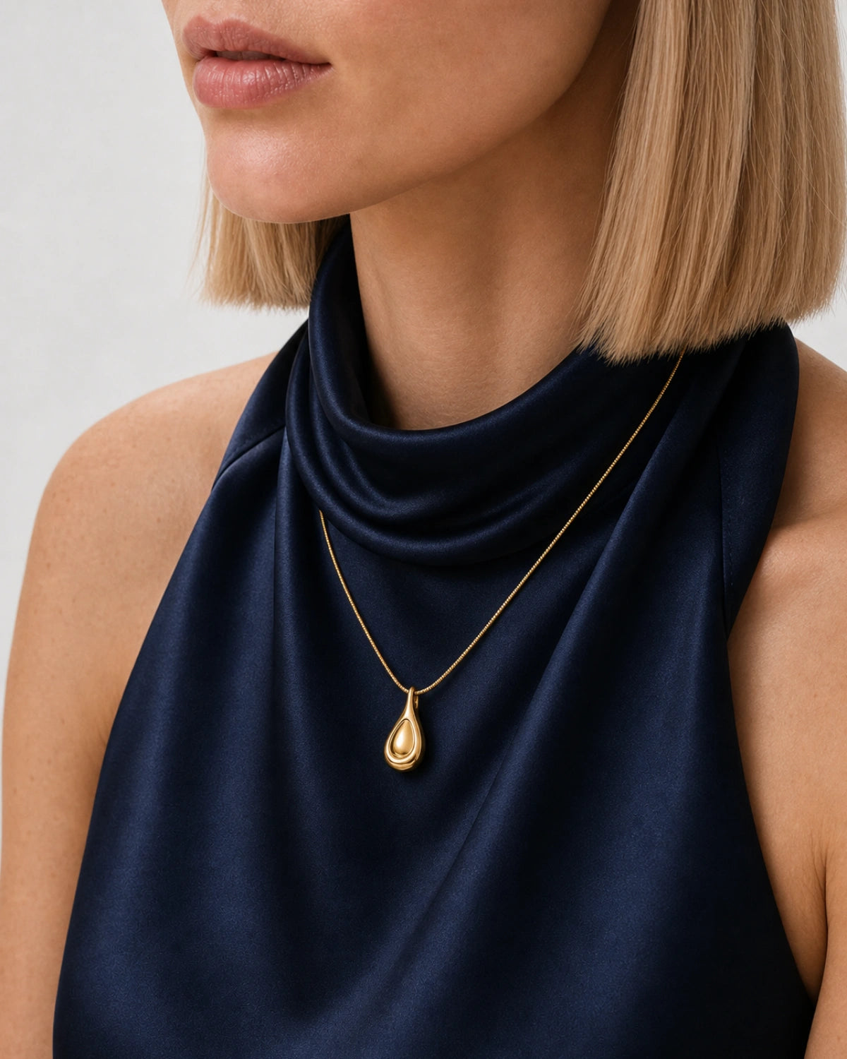Eye-free three-quarter neckline portrait of Helena wearing the Elara gold droplet necklace