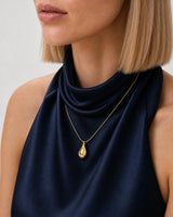 Eye-free three-quarter neckline portrait of Helena wearing the Elara gold droplet necklace