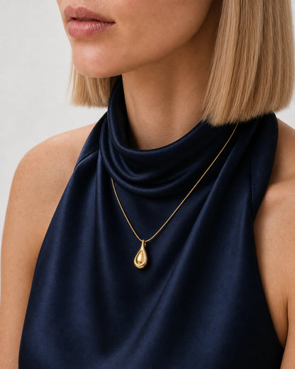 Eye-free three-quarter neckline portrait of Helena wearing the Elara gold droplet necklace