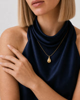 Jewellery-led shoulder and hand detail of Helena wearing the Elara gold droplet necklace