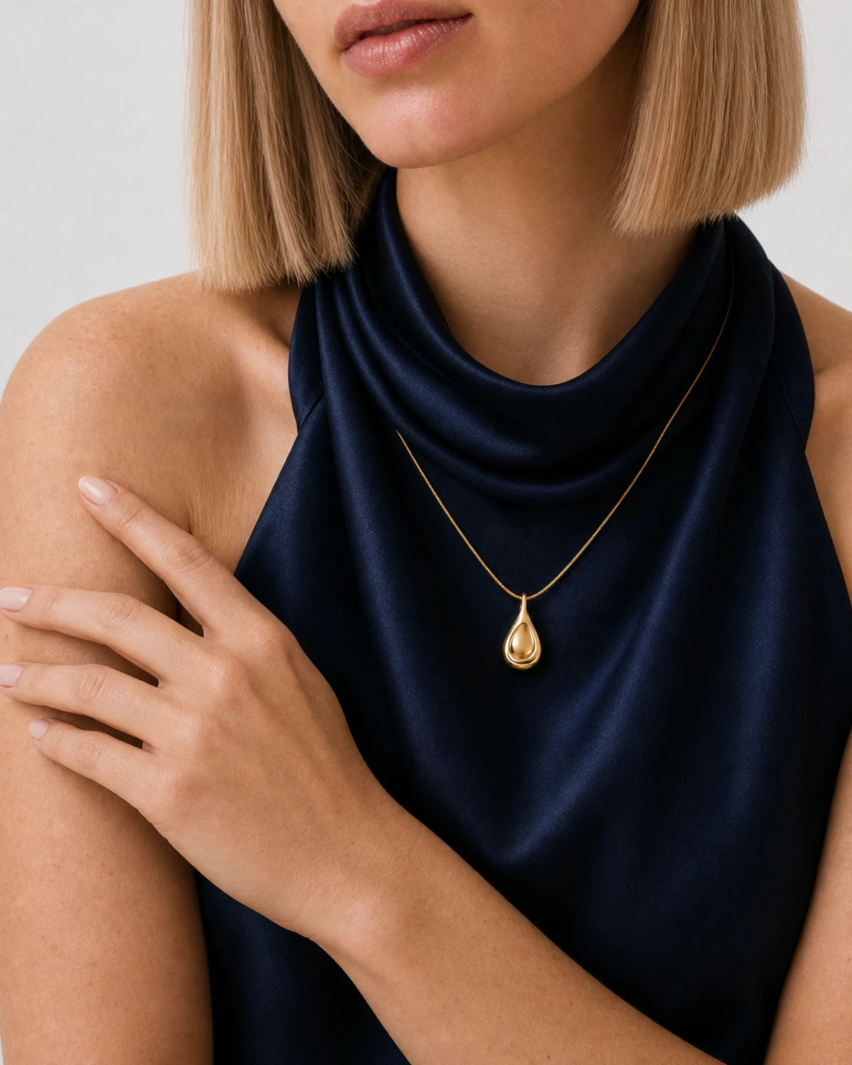 Jewellery-led shoulder and hand detail of Helena wearing the Elara gold droplet necklace