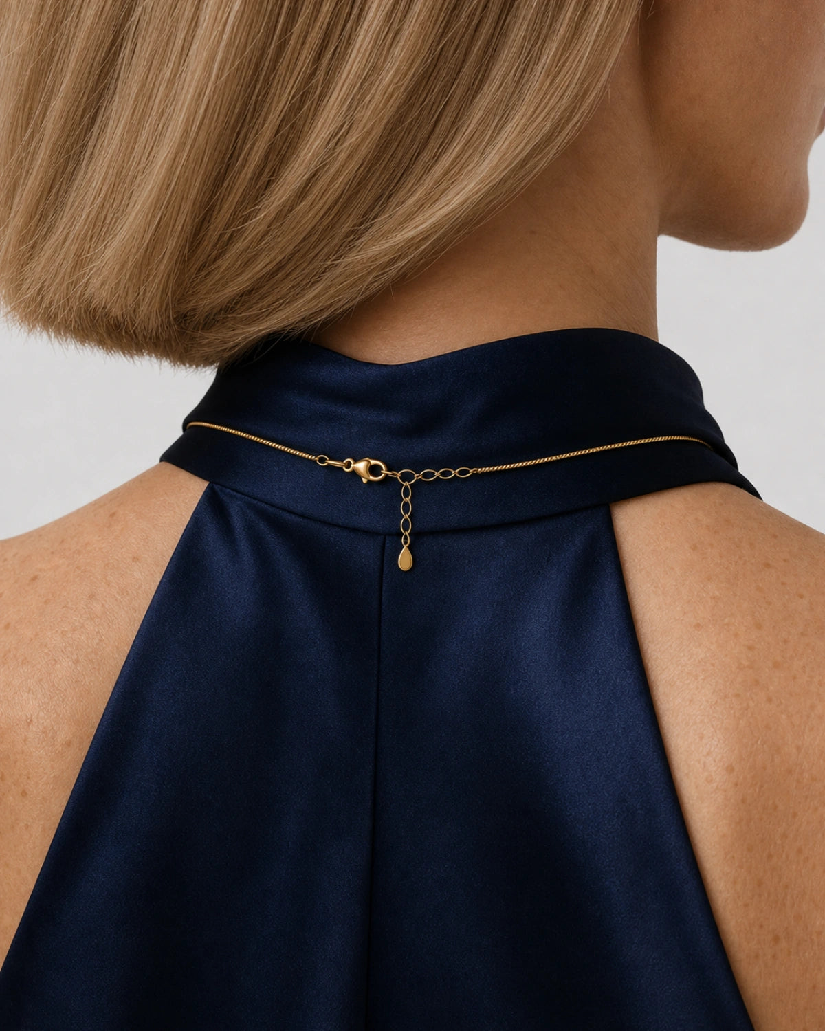 Rear nape view of Helena wearing the Elara gold necklace with clasp and extender visible