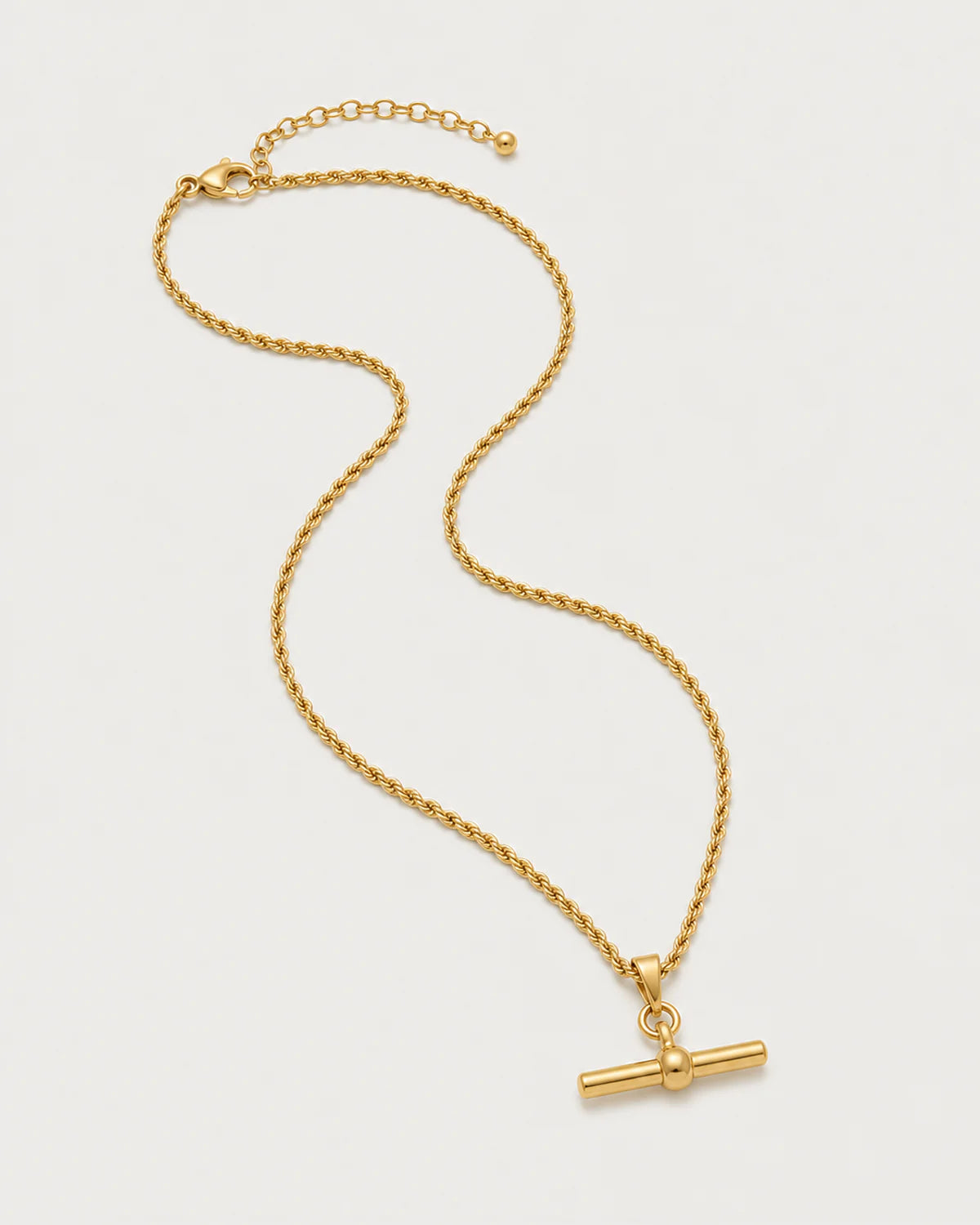 Elodie gold-tone rope T-bar necklace in an alternate arrangement on pale grey