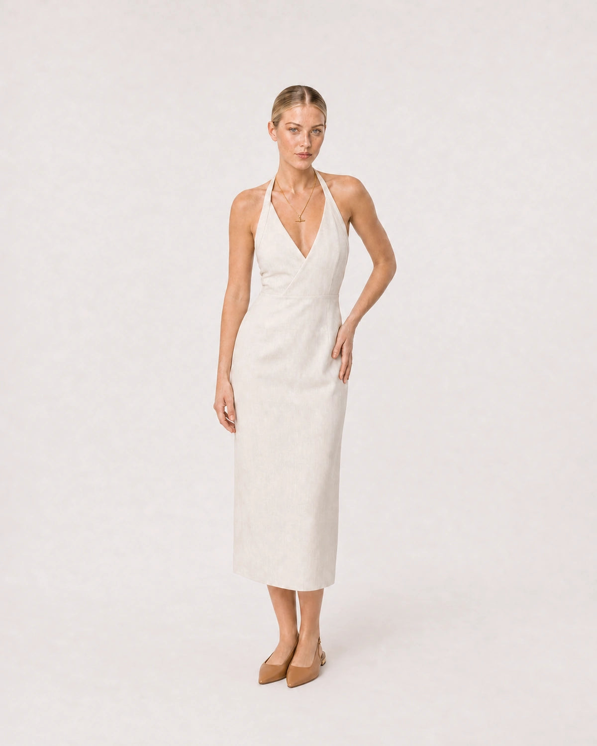 Wide studio portrait in an ivory linen halter dress featuring the Elodie necklace