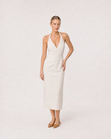 Wide studio portrait in an ivory linen halter dress featuring the Elodie necklace