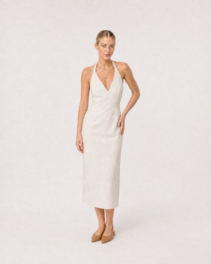 Wide studio portrait in an ivory linen halter dress featuring the Elodie necklace