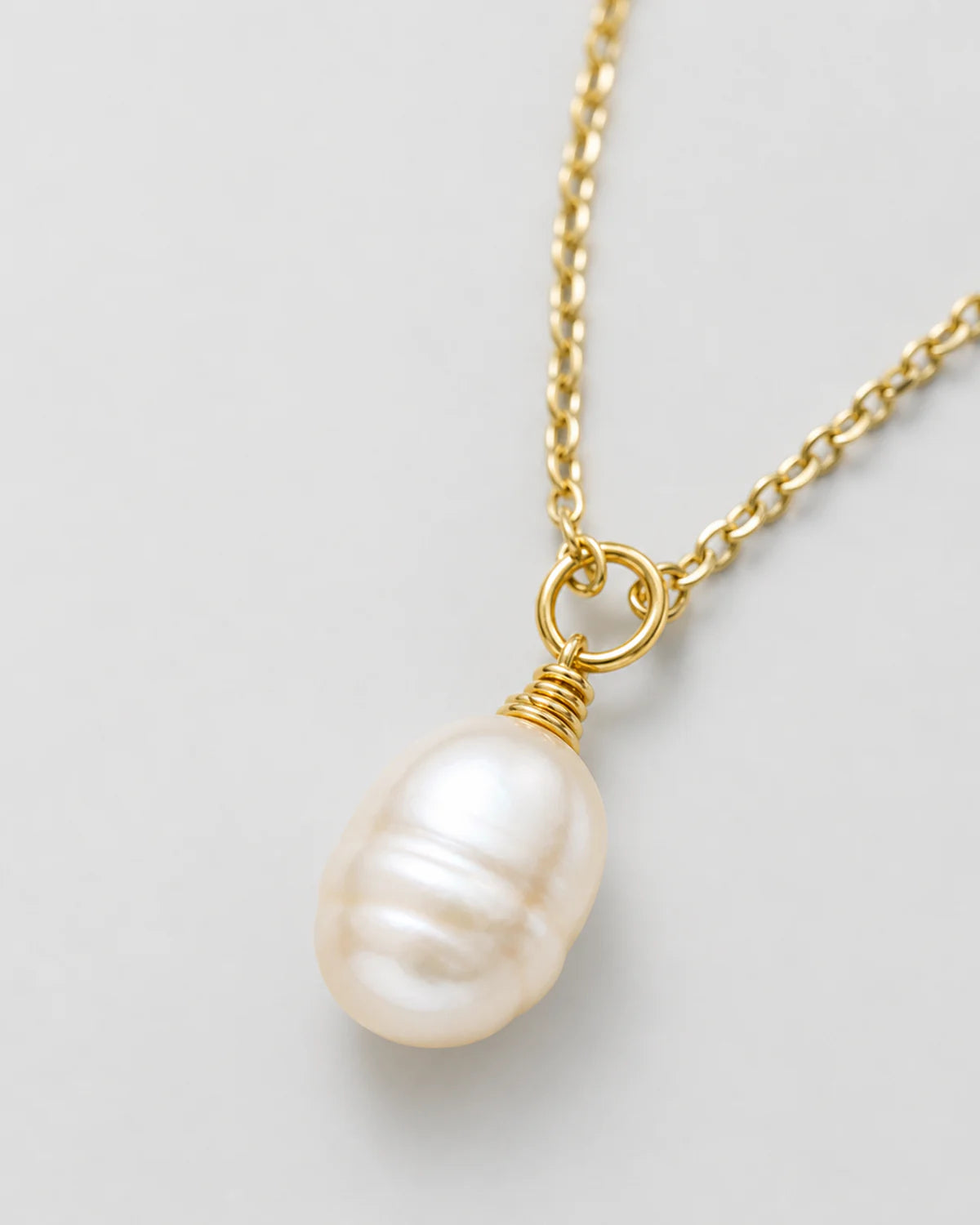 Macro view of the organic Elowen freshwater pearl and gold wire wrap