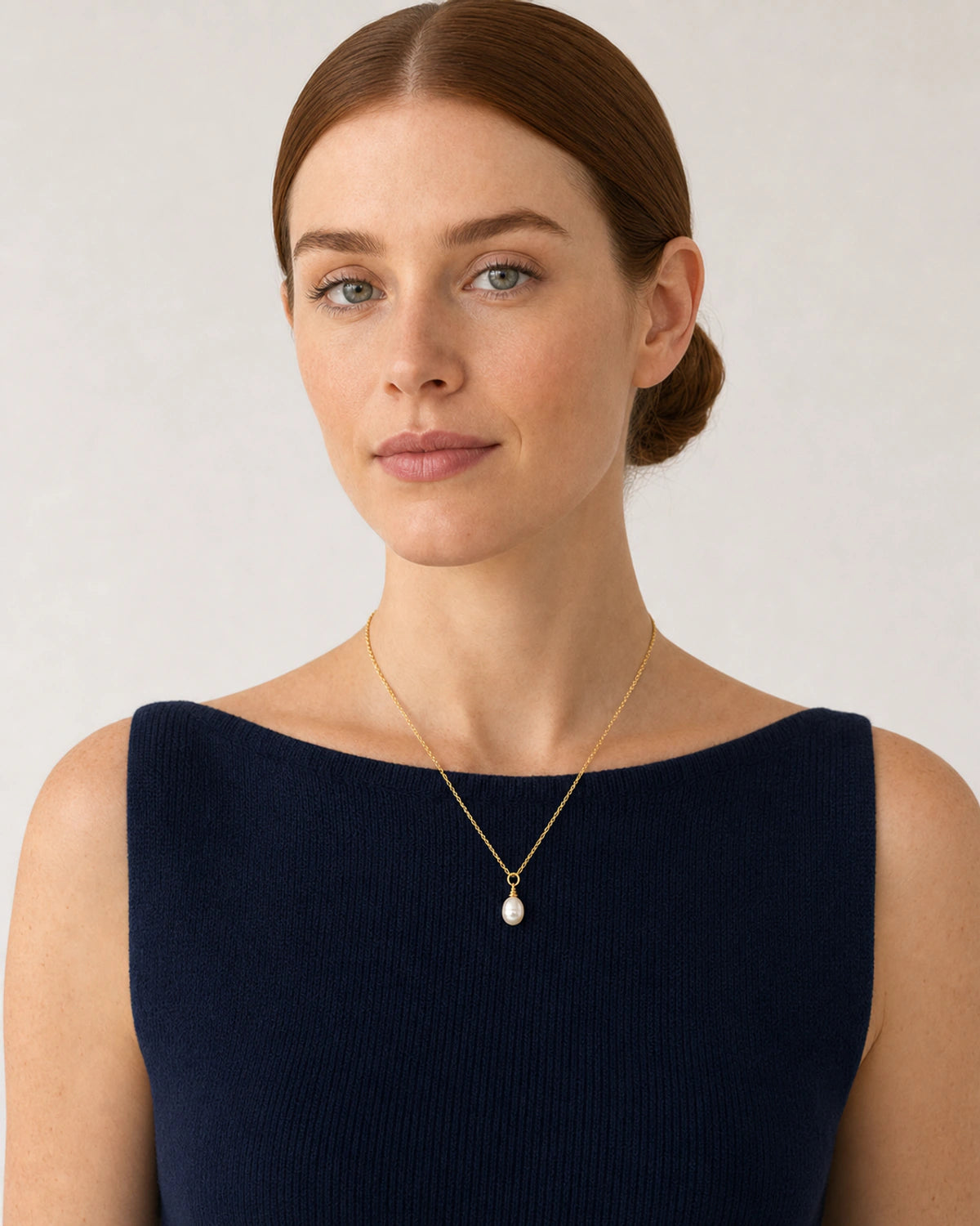 Model in a navy French Riviera knit top wearing the Elowen pearl necklace