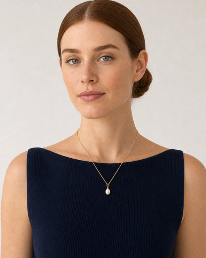 Model in a navy French Riviera knit top wearing the Elowen pearl necklace