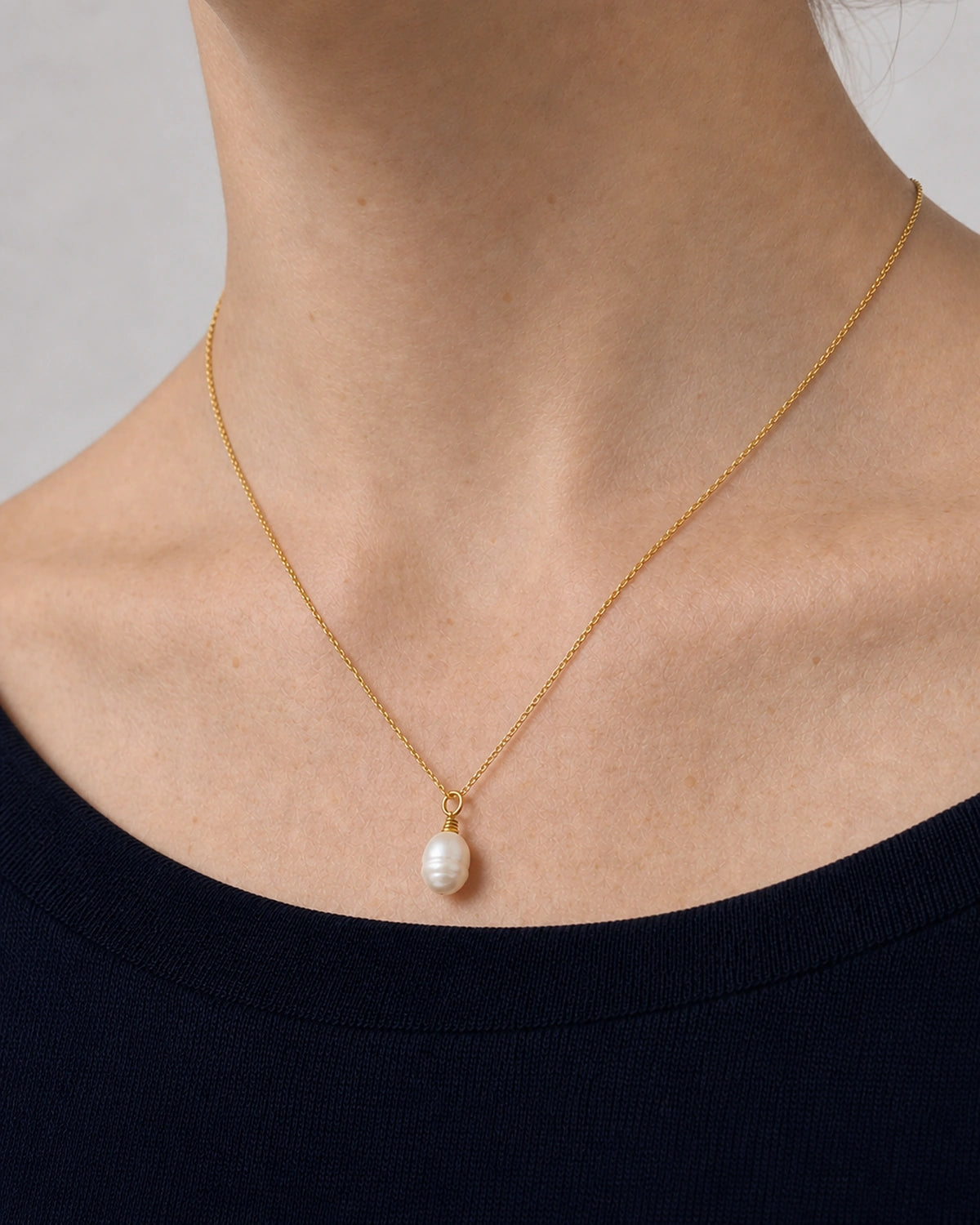Complete worn macro of the Elowen fine gold chain and organic pearl drop
