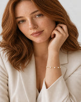 Red-haired model in ivory tailoring wearing Elowen pearl bracelet