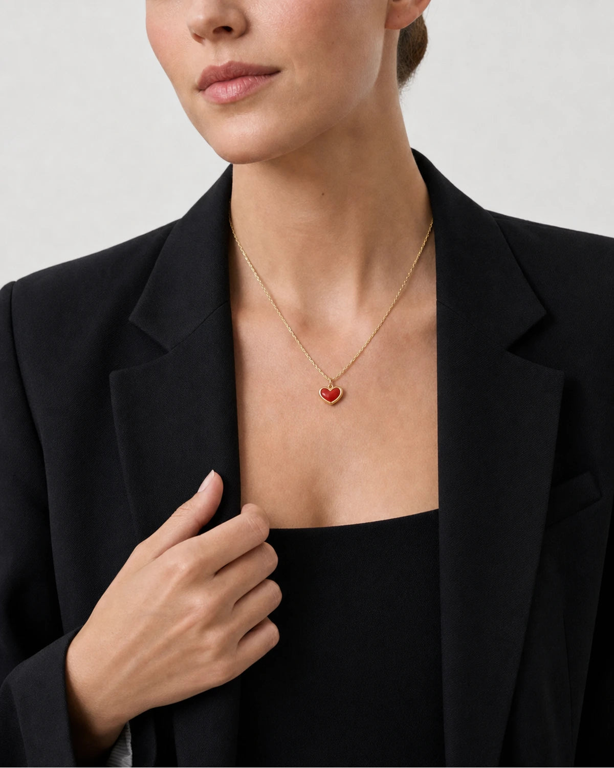 Human-scale wearing detail of the Estelle red enamel heart pendant