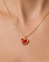 Extreme on-body macro of the Estelle red enamel heart and gold chain