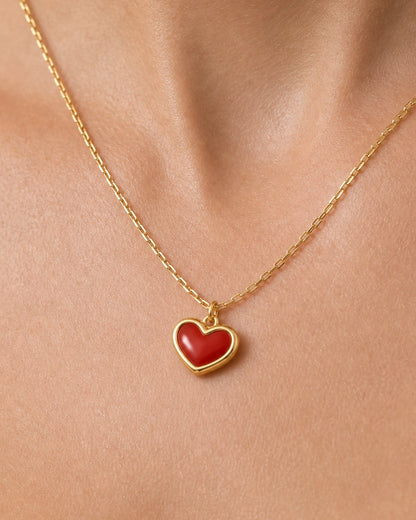 Extreme on-body macro of the Estelle red enamel heart and gold chain