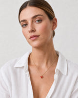 Model in a white linen Riviera shirt wearing the Estelle red enamel heart necklace