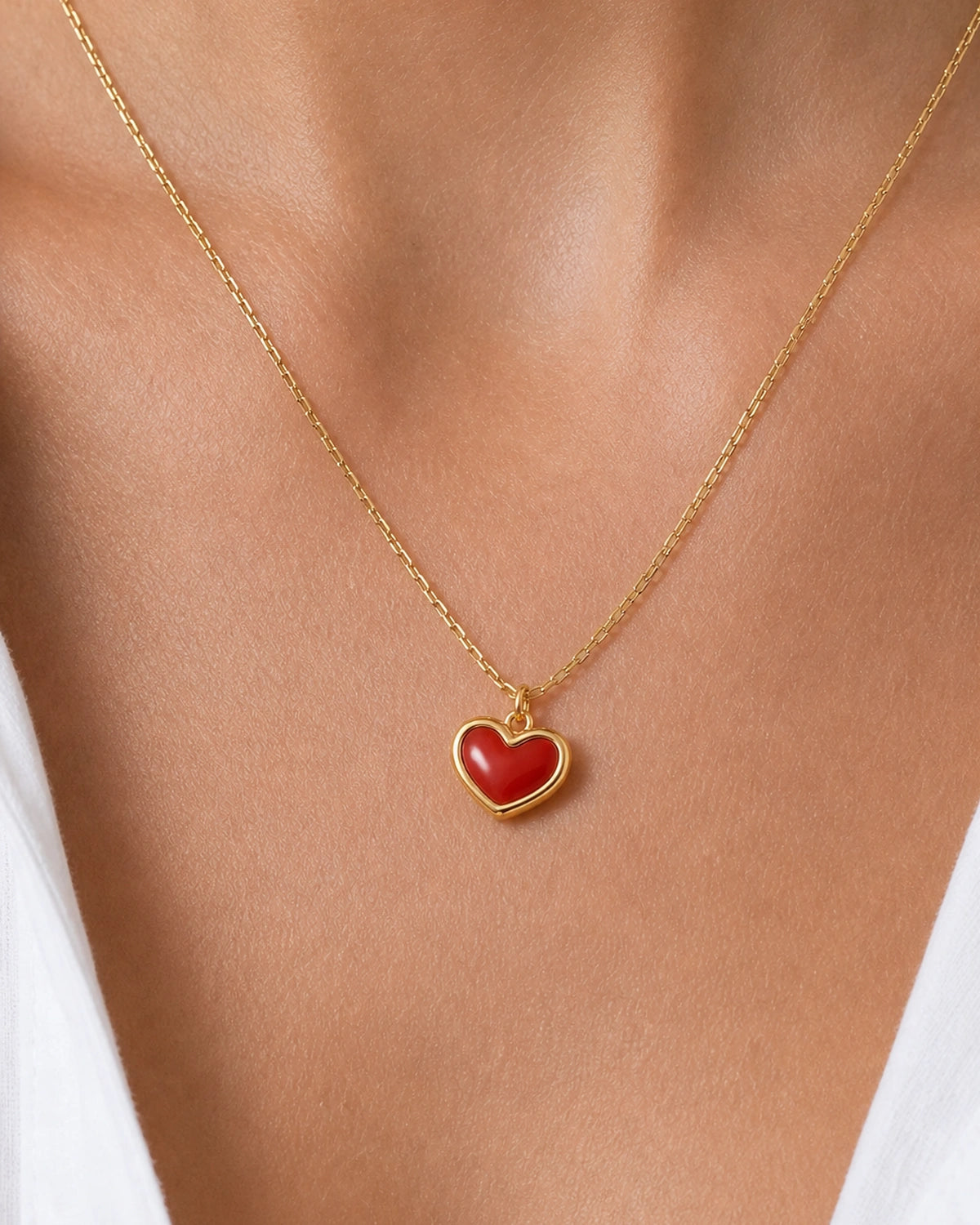 Extreme on-body macro of the Estelle gold and red enamel heart necklace