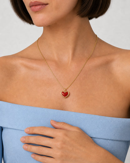 Alternate worn detail of the Estelle red enamel heart necklace with a relaxed hand below