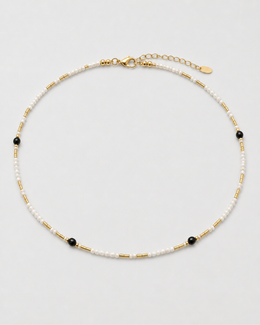 Isla ivory, black and gold beaded choker arranged on seamless pale dove-grey