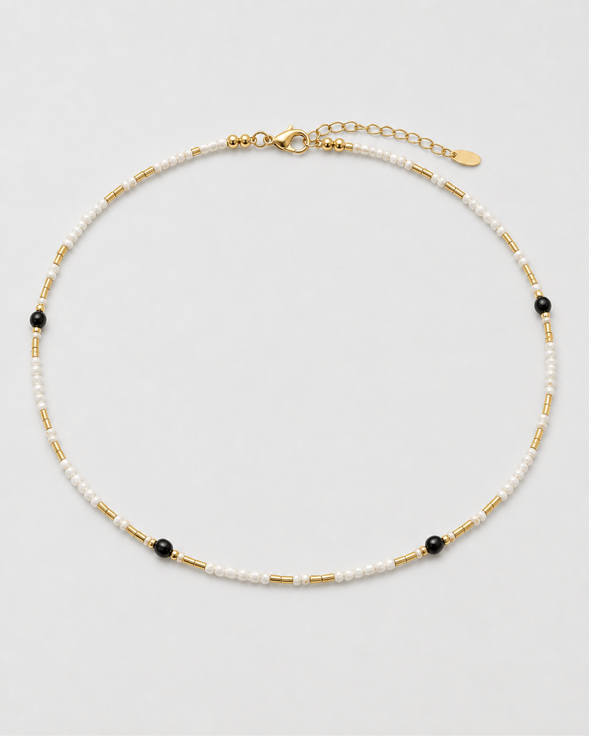 Isla ivory, black and gold beaded choker arranged on seamless pale dove-grey