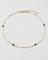 Isla ivory, black and gold beaded choker arranged on seamless pale dove-grey
