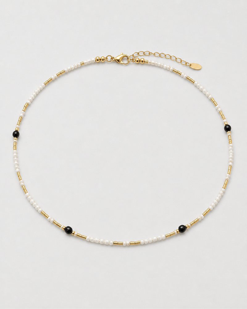 Isla ivory, black and gold beaded choker arranged on seamless pale dove-grey