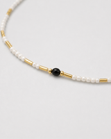 Macro of Isla ivory seed beads, black accent bead and polished gold tube spacers