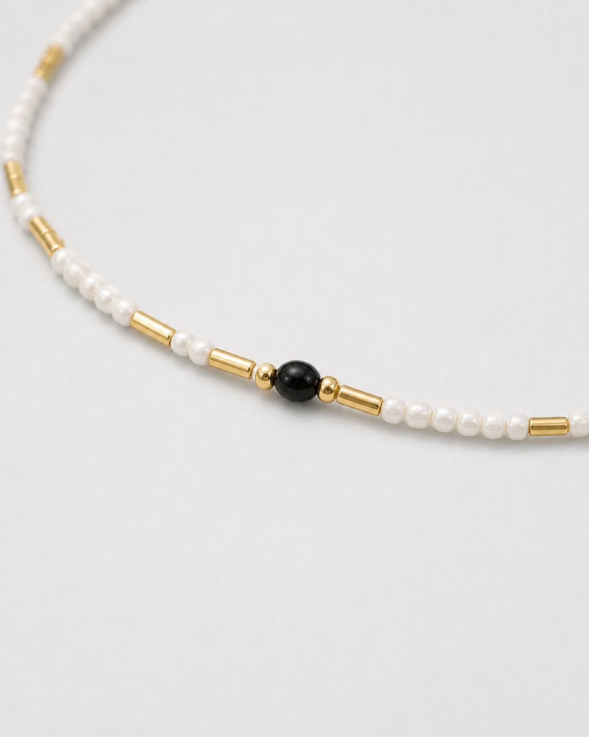 Macro of Isla ivory seed beads, black accent bead and polished gold tube spacers