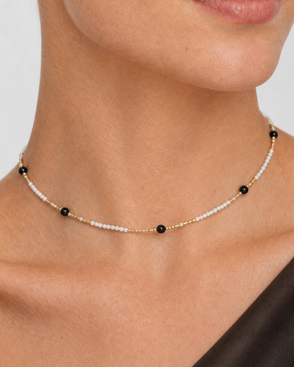 Extreme on-body macro of Isla seed beads, black accents and gold tube spacers