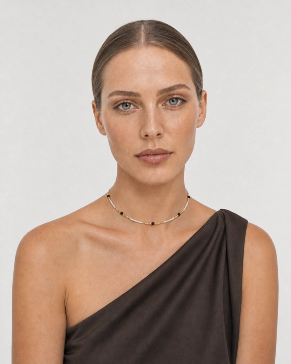 Model in asymmetric silk wearing the Isla ivory black and gold beaded choker