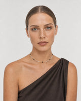 Model in asymmetric silk wearing the Isla ivory black and gold beaded choker