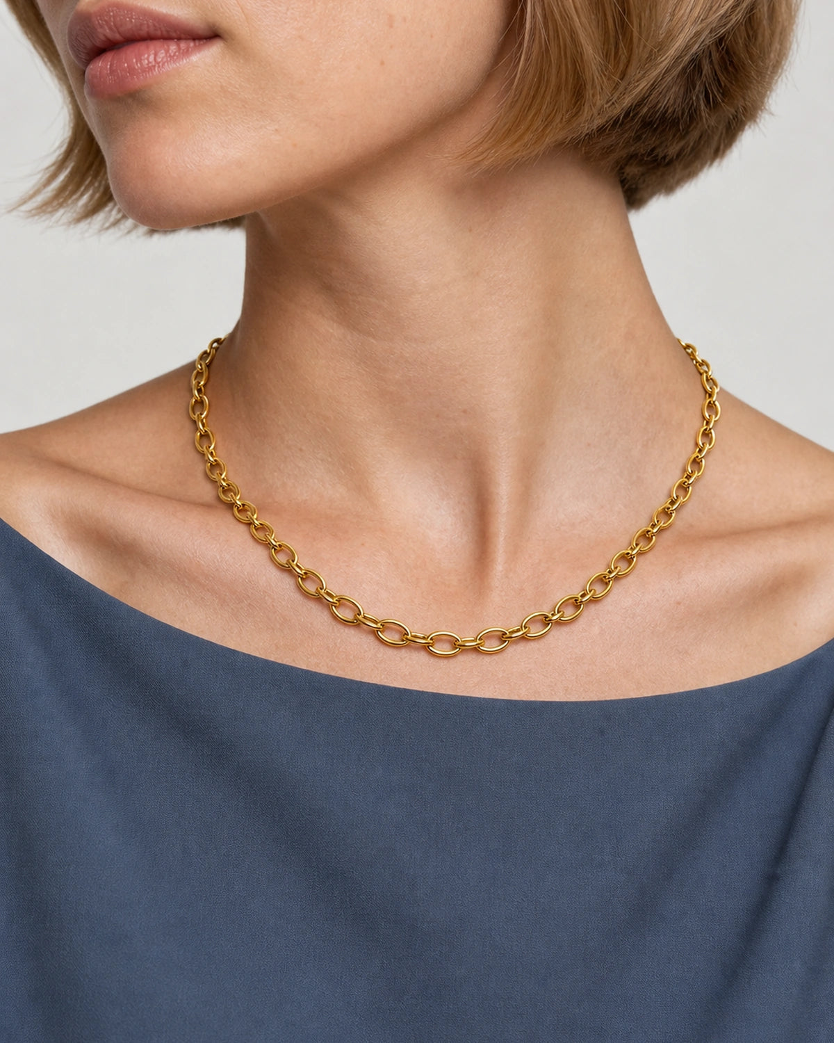 Mouth-down three-quarter wearing view of the Liora gold orbit-link necklace