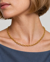 Complete Liora gold orbit-link necklace worn at the collarbone in an extreme macro view
