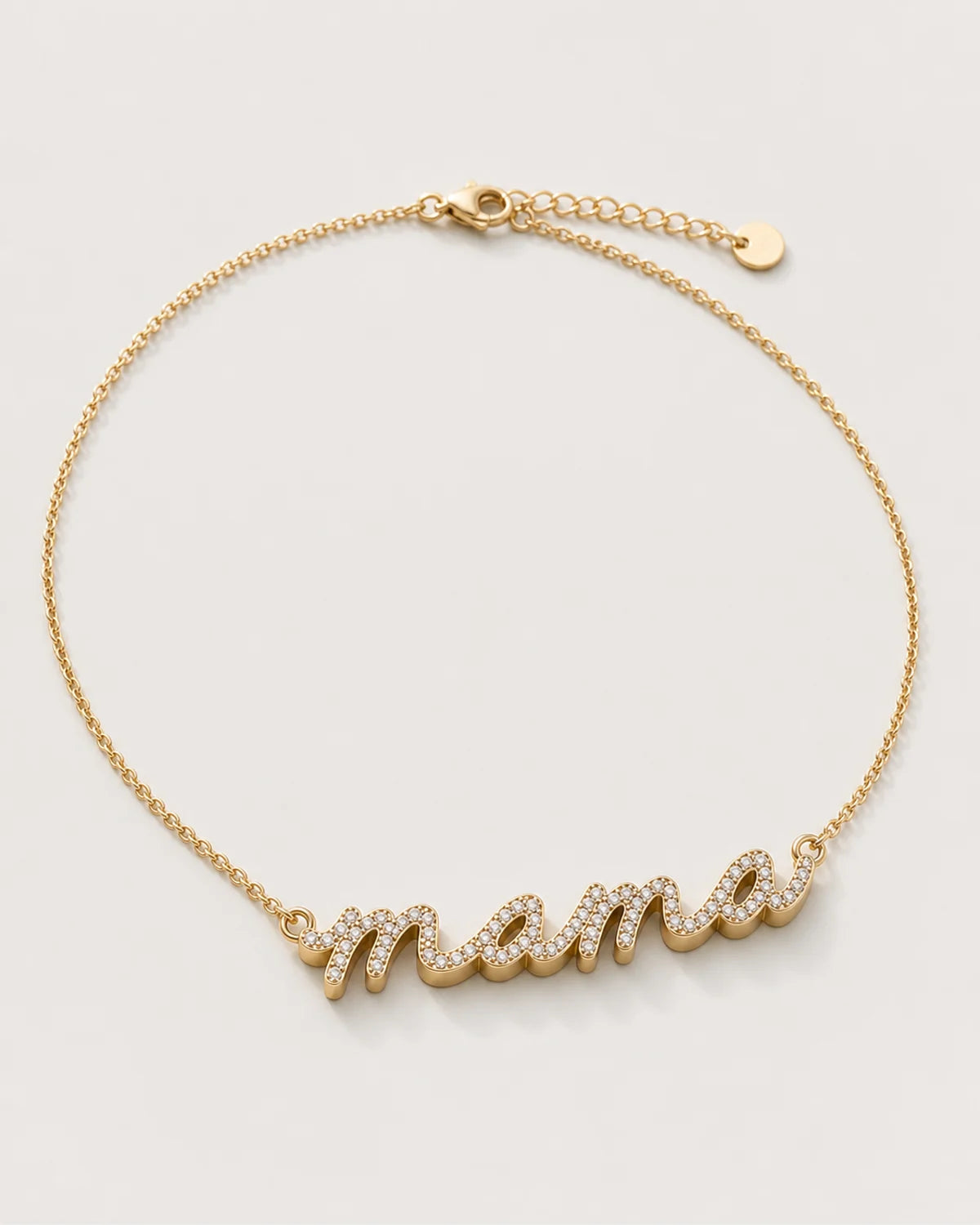 Liora gold sculpted pavé mama necklace on a seamless pale dove-grey studio background