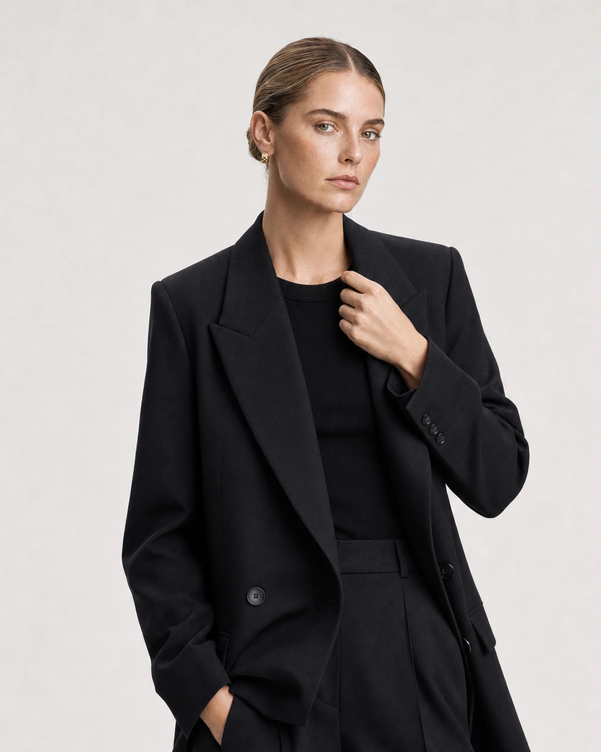 Human-scale studio view of Lisette gold huggies with black tailoring