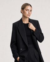 Human-scale studio view of Lisette gold huggies with black tailoring