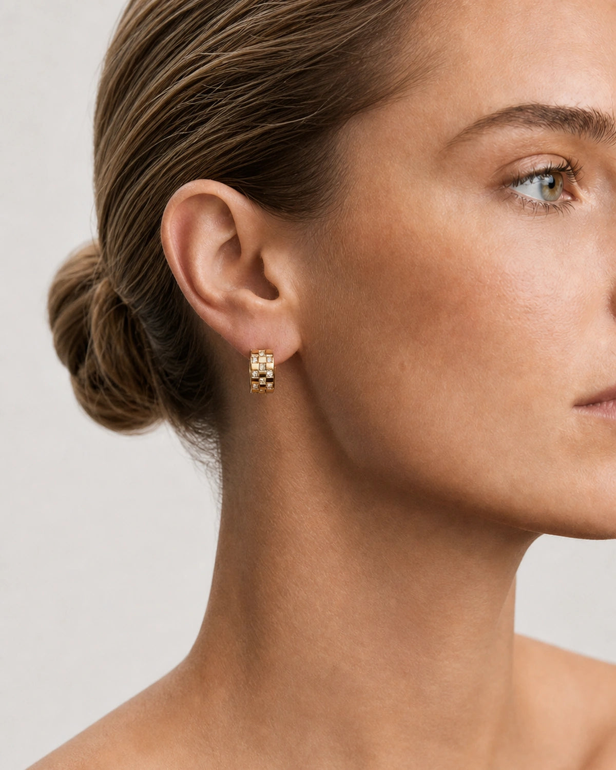 Close side portrait showing one Lisette gold checkerboard crystal huggie