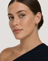 Full-face portrait of Cecily wearing the gold Lisette checkerboard huggies